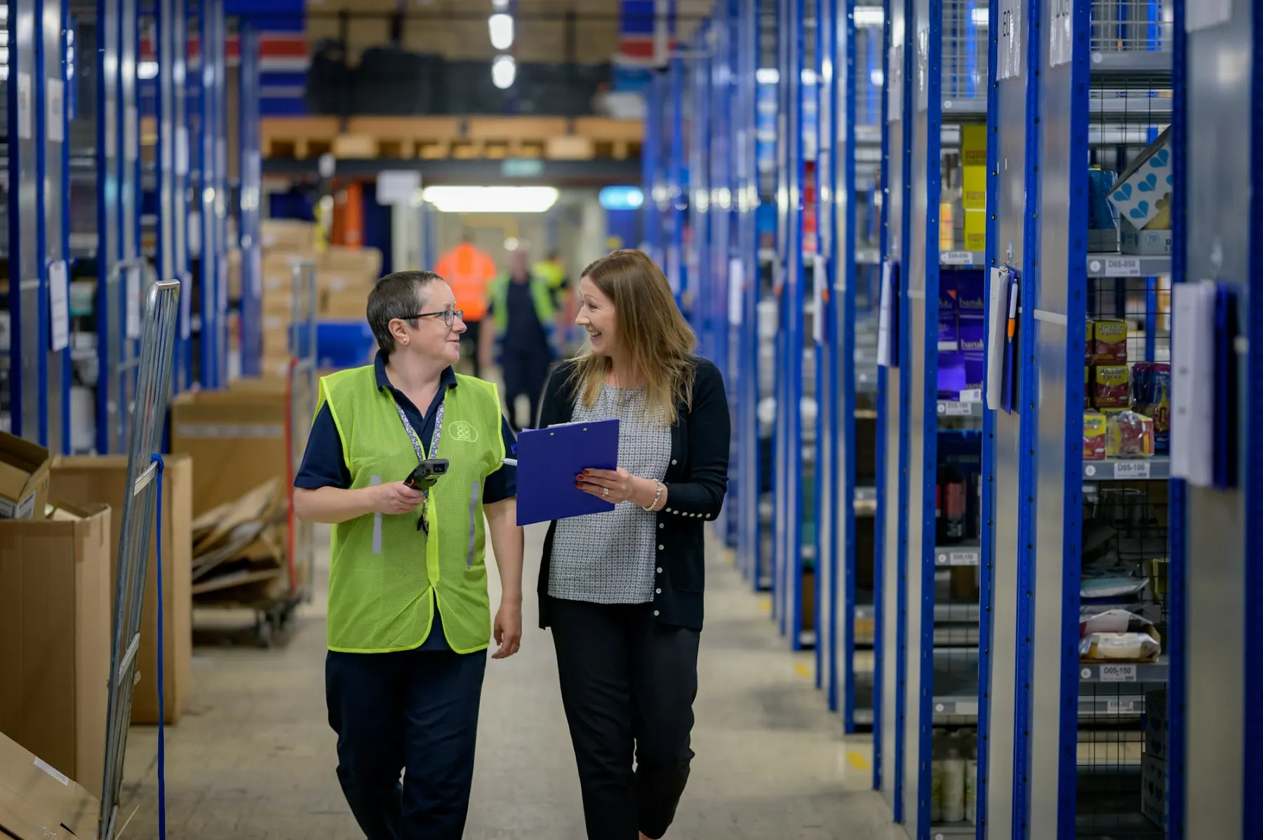 Warehouse staff with a handheld scanner reviewing orders in an aisle